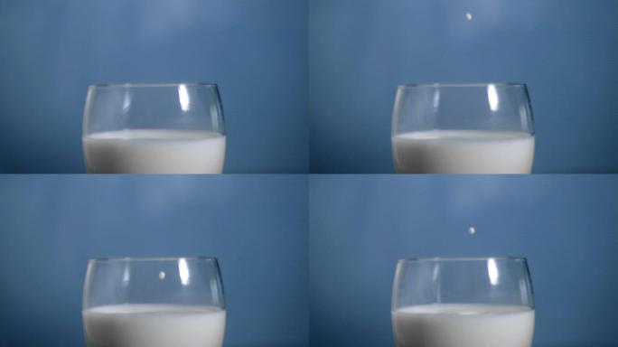 在蓝色背景下，牛奶中液滴以超慢的运动下落