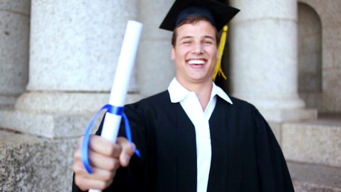 快乐的学生拿着他的文凭在大学前面