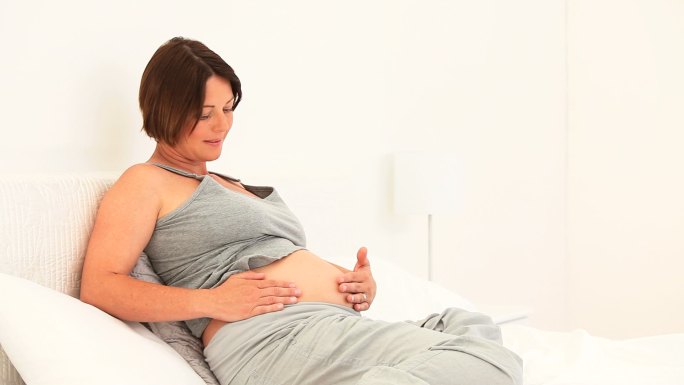 一个孕妇在沙发上摸着肚子