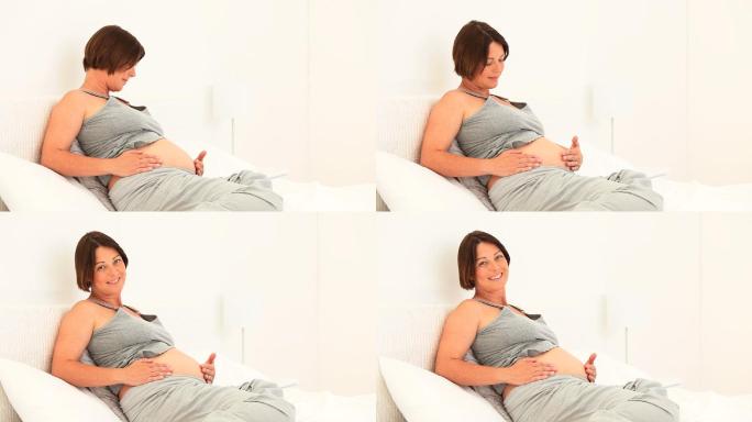 一个孕妇在沙发上摸着肚子