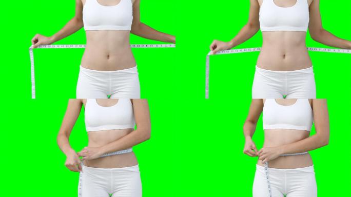 一个女性测量腰围特写镜头，在绿色背景下