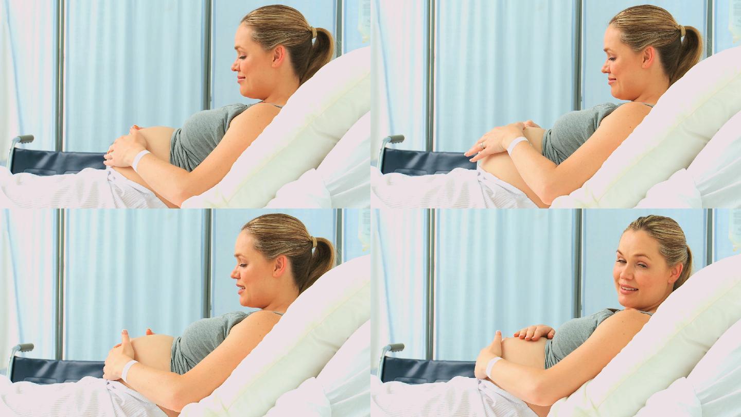 一名孕妇在诊所的床上抚摸着自己的肚子