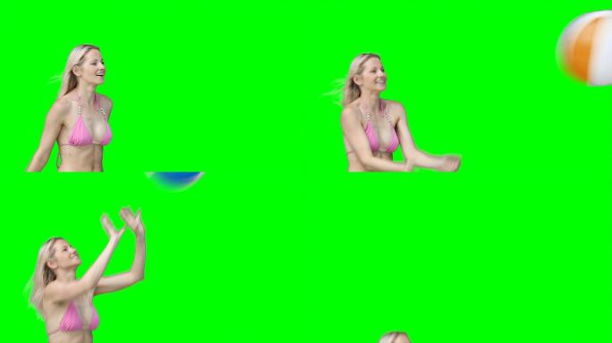 一个穿着比基尼的女人在绿色背景下来回传递一个沙滩球