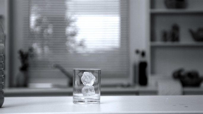 两个冰块以慢动作落在空玻璃杯里