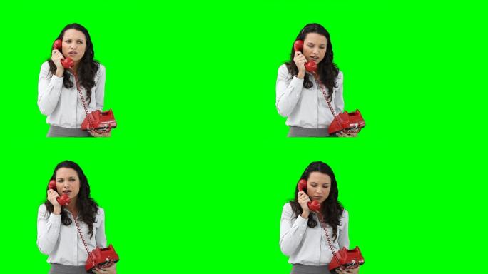 在绿色背景下，一位女商人正在用红色电话与某人交谈
