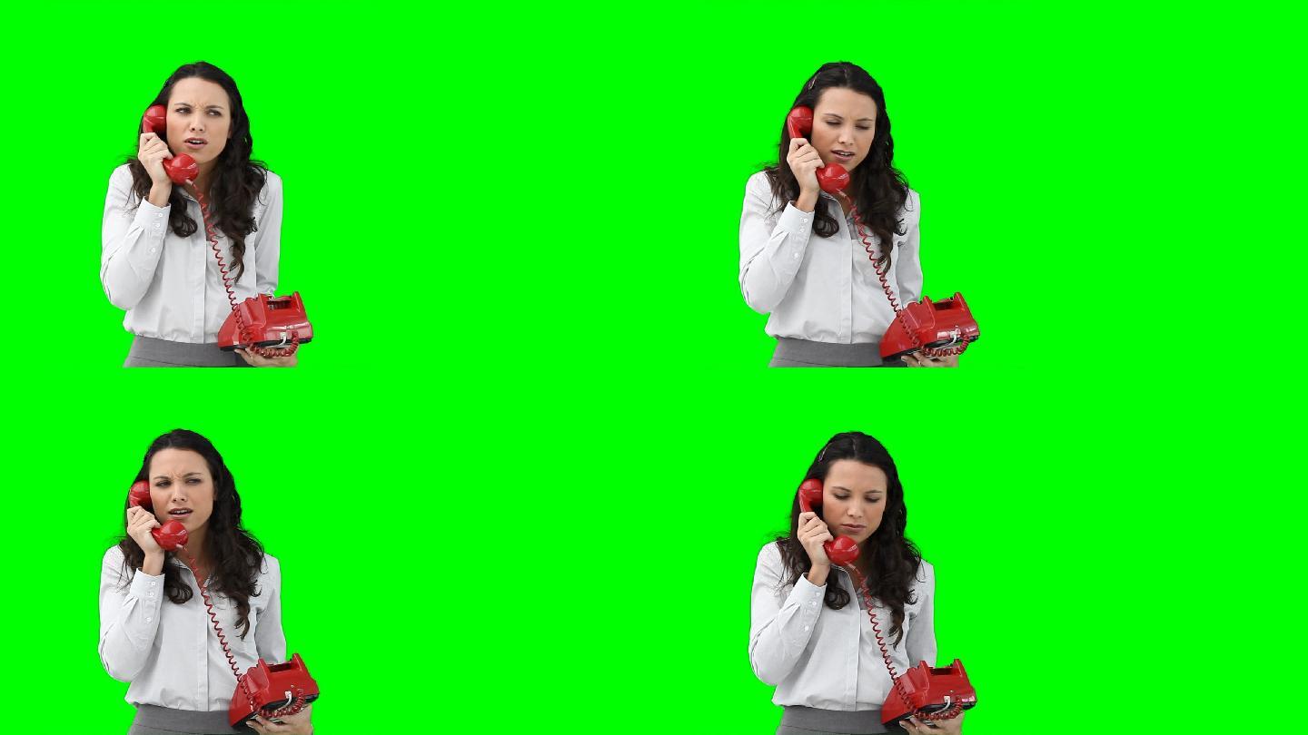 在绿色背景下，一位女商人正在用红色电话与某人交谈
