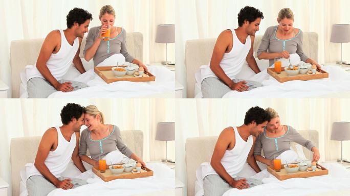 可爱的夫妇在床上吃早餐
