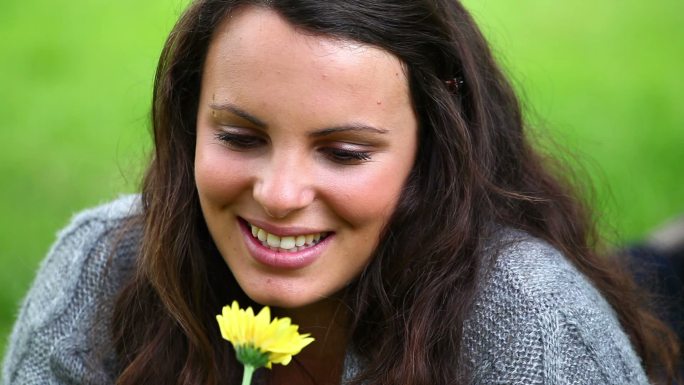 Smiling brunette holding while smelling a flower i