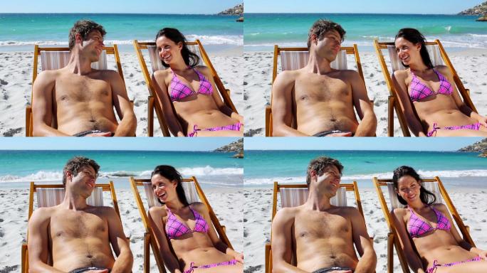 一对幸福的夫妇躺在沙滩上的躺椅上