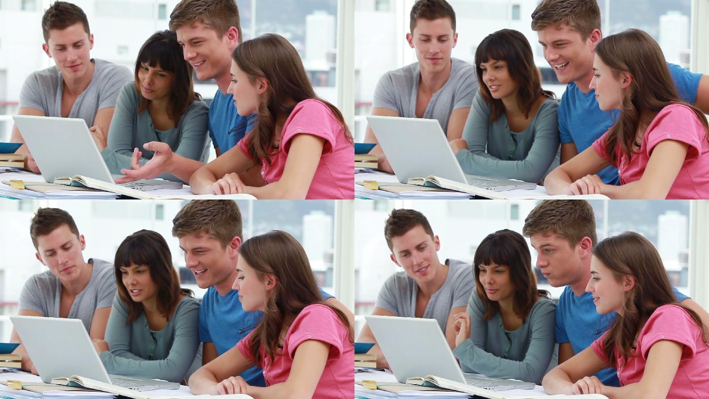 微笑的学生一起使用笔记本电脑在一个明亮的房间