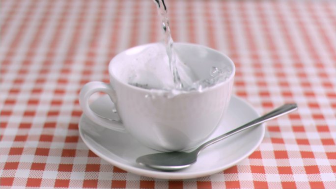 以超慢的动作将水倒入装有茶的杯子中