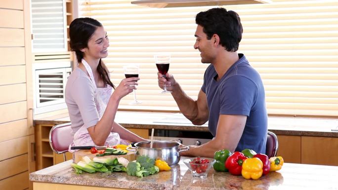 微笑的夫妇在厨房里喝着葡萄酒
