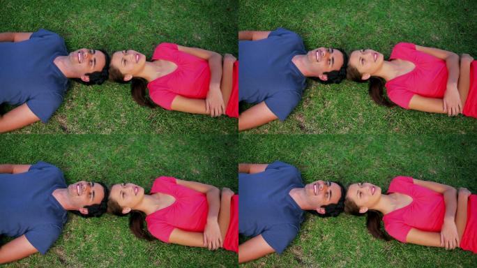 一对微笑的夫妇躺在公园的草地上