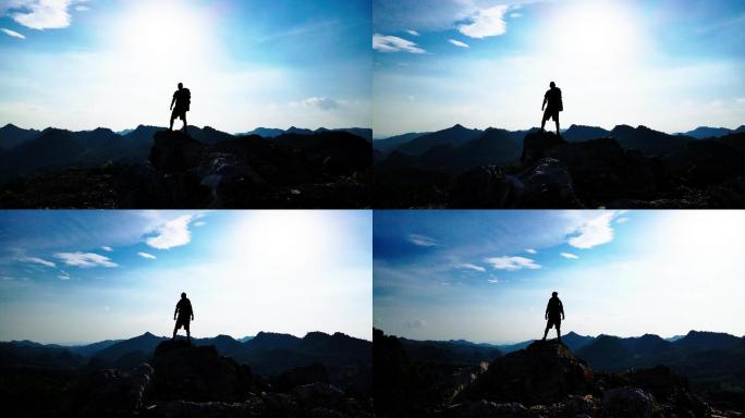 男人背登山包成功登顶眺望远方永攀高峰登山