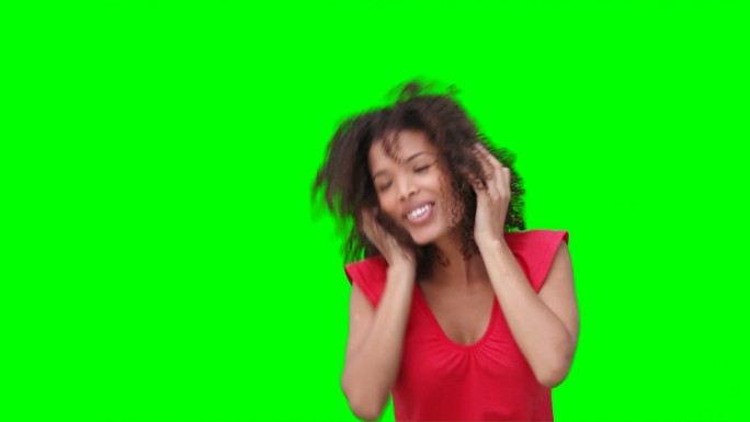 一个女人戴着耳机在绿色背景下听音乐