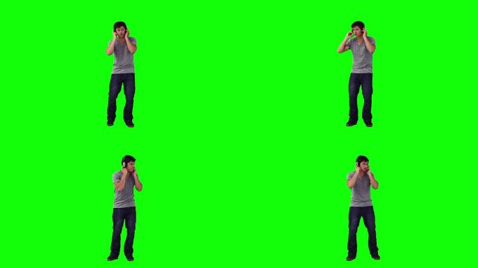 一名戴着耳机的男子在绿色背景前跳舞