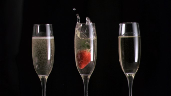 草莓在香槟中以超慢的动作落在黑色的背景下