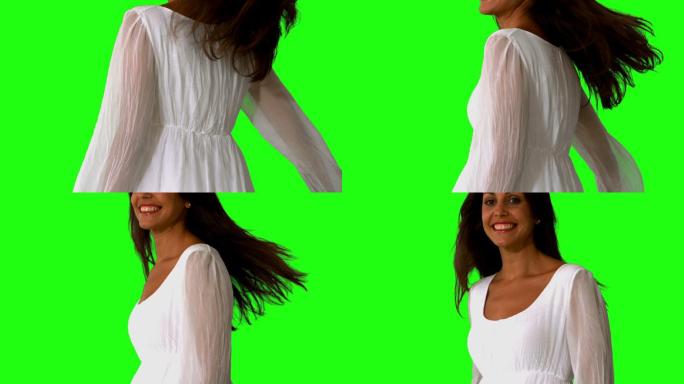穿着白色裙子的女孩在绿色屏幕上旋转的慢动作特写