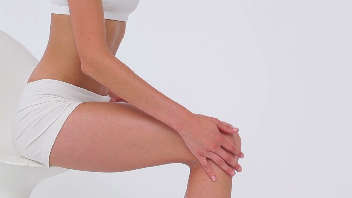 一个女性在白色背景下按摩腿部