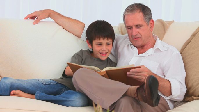一个男孩和他爷爷在沙发上看一本相册