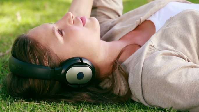 一个女人戴着耳机在公园里听音乐