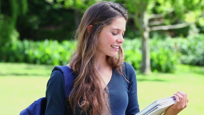 微笑的年轻女子拿着一个笔记本在公园里