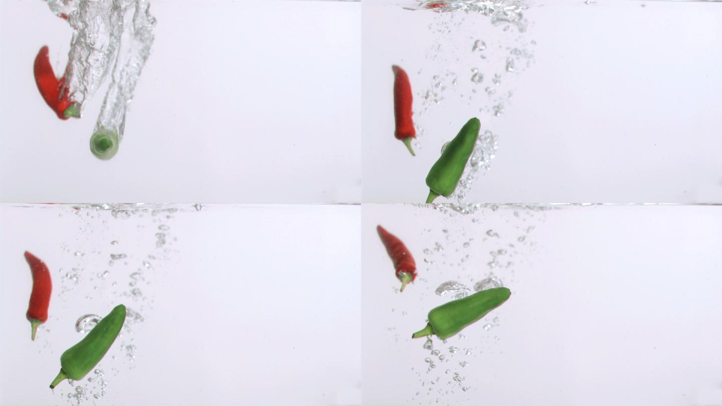 红色和绿色辣椒水中落下慢镜头，在白色背景下