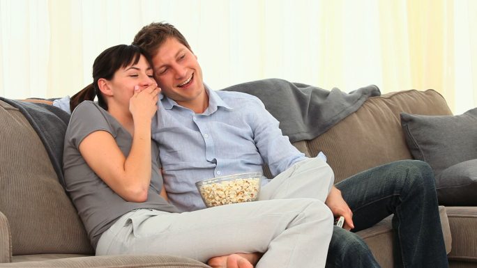 一对年轻夫妇在沙发上看电视