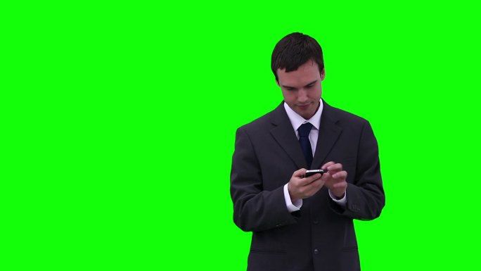 一个商人一边用手机打字，一边以绿色的背景环顾四周