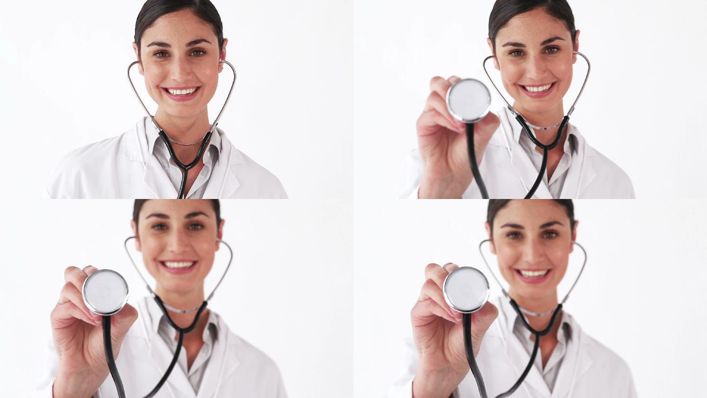 微笑的医生在白色的背景下展示她的听诊器