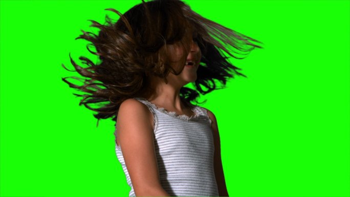 在慢动作的绿色屏幕上，小女孩甩动她的头发