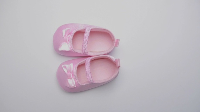 粉红色婴儿鞋在旋转白色表面