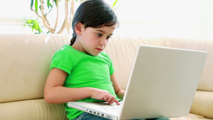 可爱的小女孩在客厅用笔记本电脑
