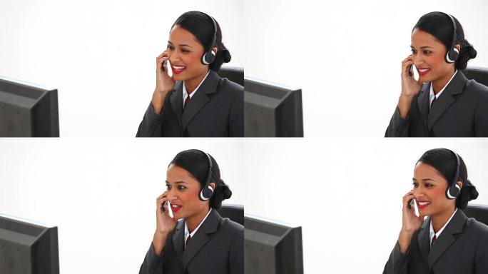 女商人在她的办公桌上使用耳机对抗白色背景