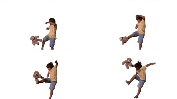 一个白人男孩跳跃踢毛绒玩具慢镜头，在白色背景下