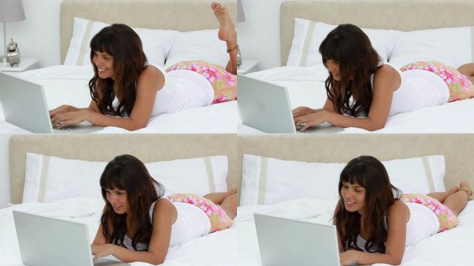 一个躺在卧室里用笔记本电脑的快乐女人