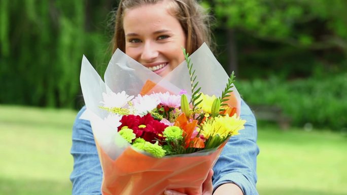 快乐的女人捧着一束花在乡间