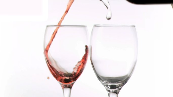 葡萄酒和水以超级慢的动作倒在白色的背景下