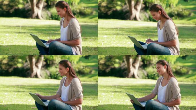 在公园里坐着用笔记本电脑的女人