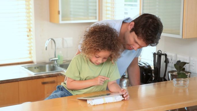 一个男孩和他爸爸在厨房里用电子书