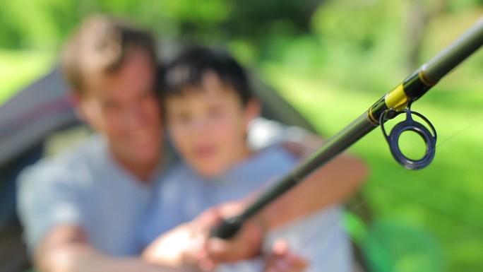 快乐的父亲和儿子拿着鱼竿在农村