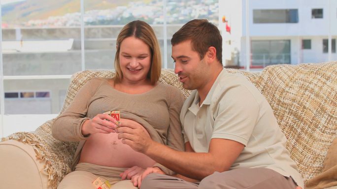 一个男人将积木放在怀孕老婆的肚子上