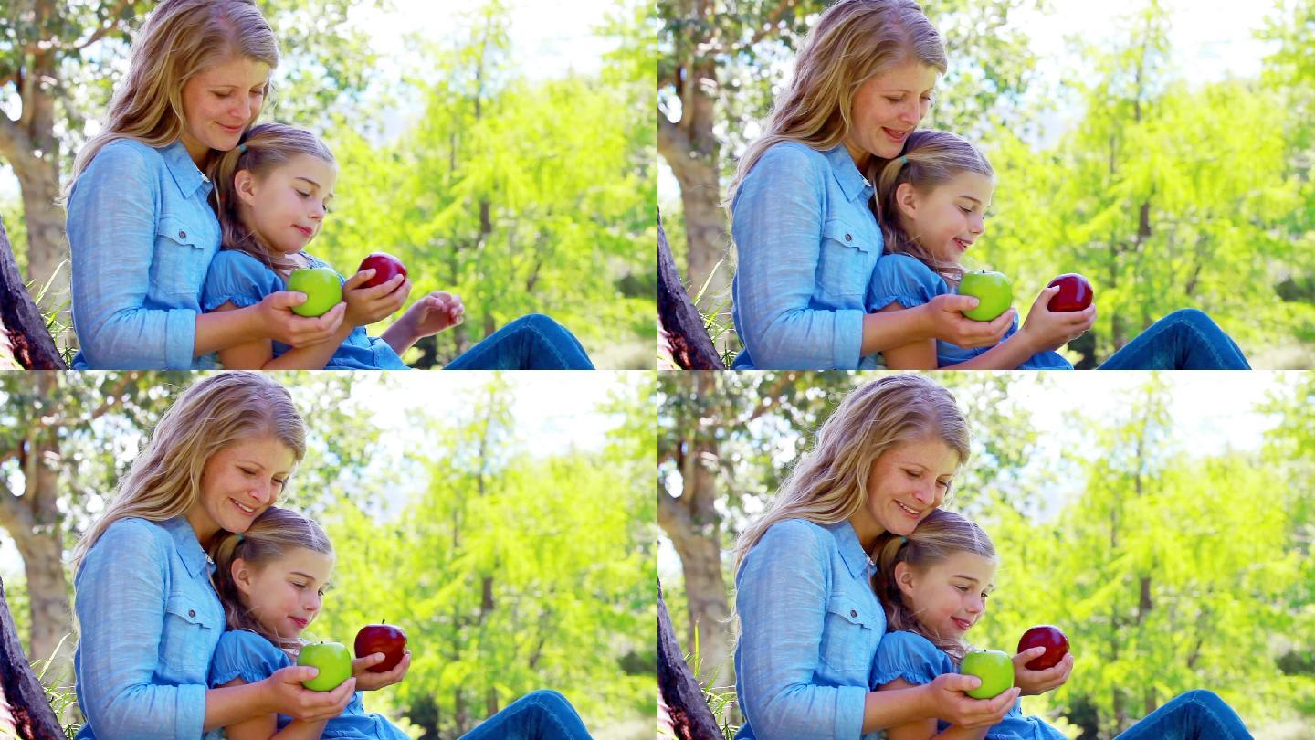 女儿和母亲拿着苹果在一个apark