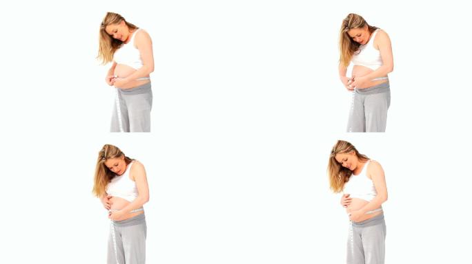 孕妇用卷尺测量自己的肚子，在白色背景下