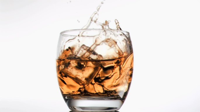 白色背景下的苏格兰威士忌中，冰块以超慢的动作下落