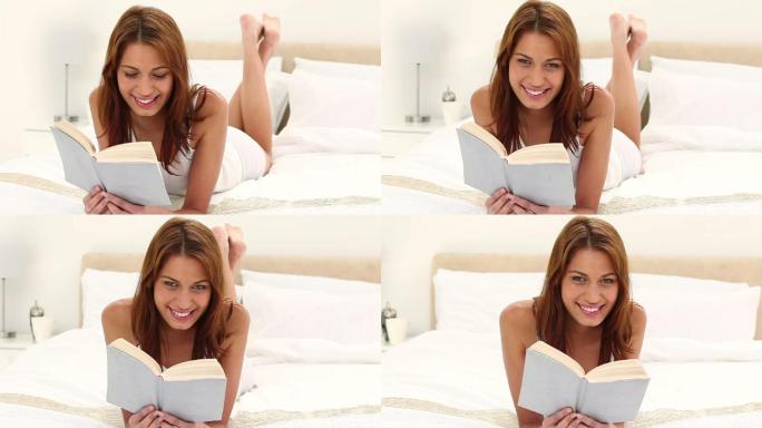 一个亚洲女孩趴在床上看书