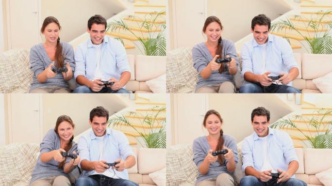 男人和女人坐在沙发上一起玩主机游戏，笑着