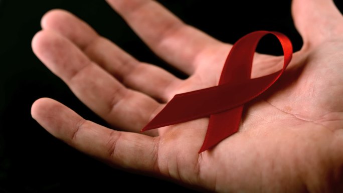 爱滋病红丝带标志在慢动作落在一个人的手上
