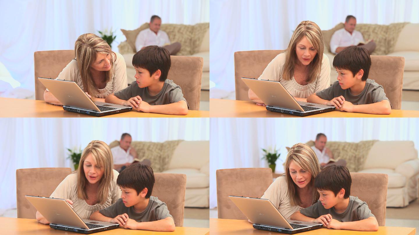 一位女士和她的孙子在客厅的桌子上使用笔记本电脑