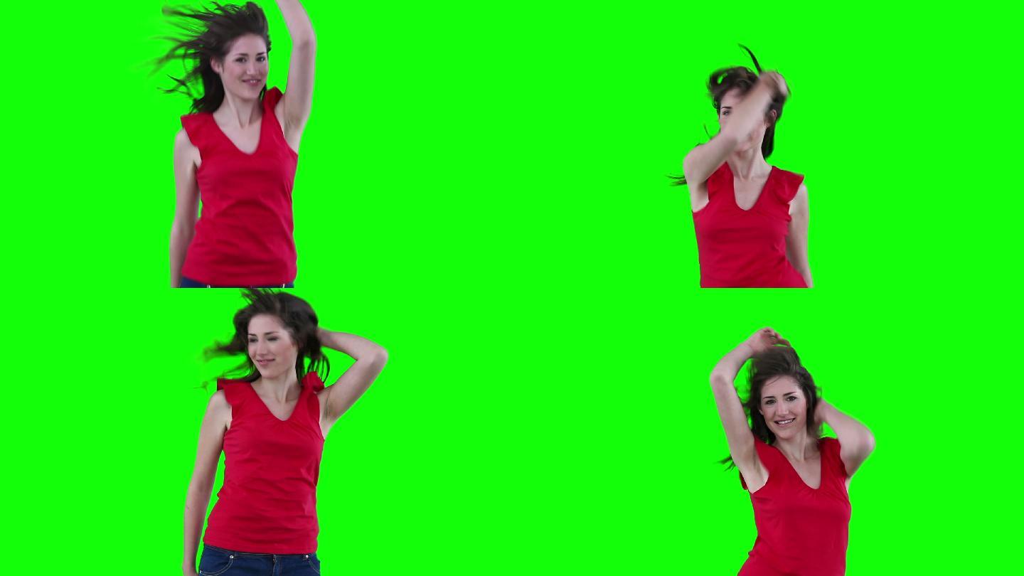 女人感觉她的头发，因为她是跳跃在一个绿色的背景